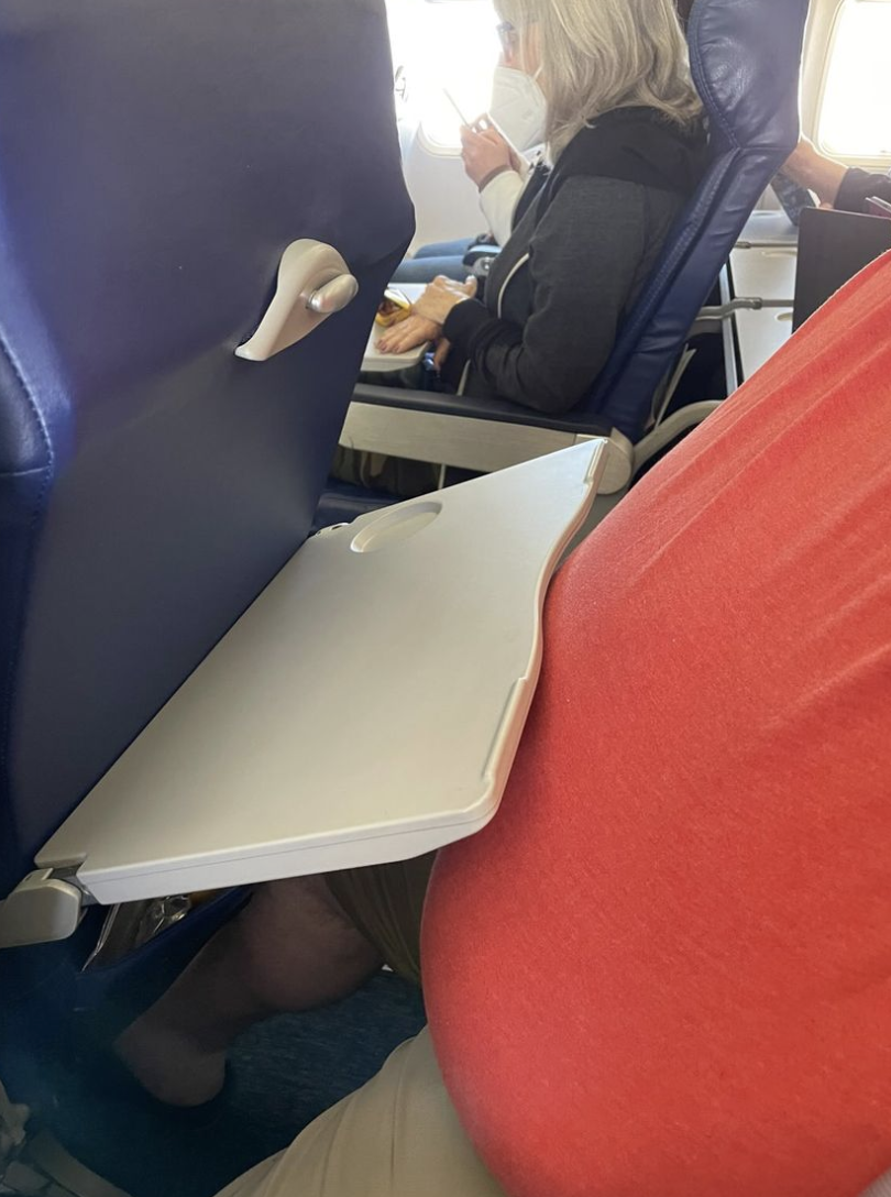 tray table stuck between the person and the seat
