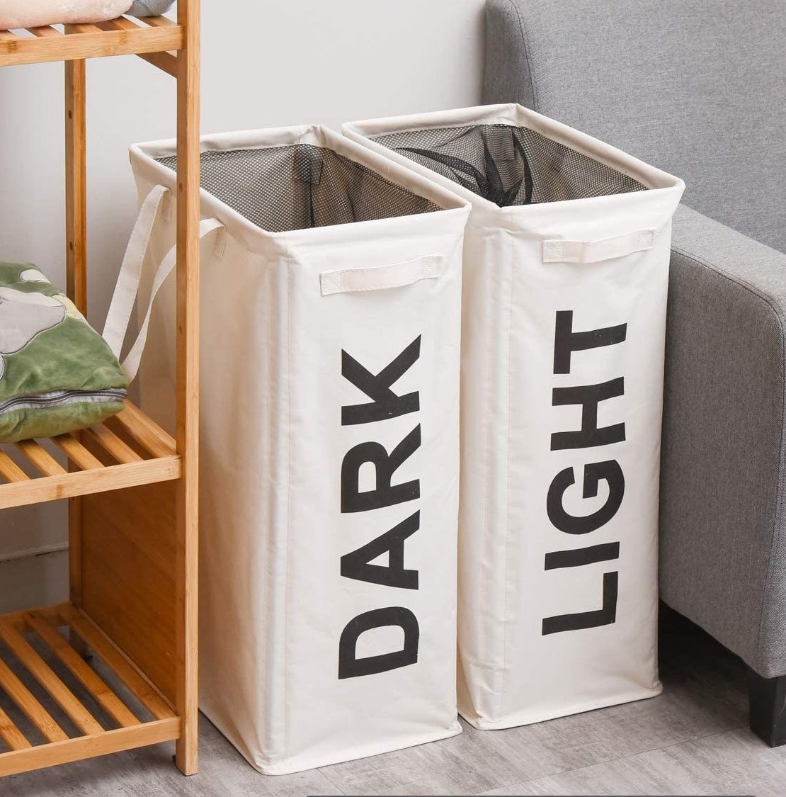 a pair of light and dark hampers tucked next to a couch