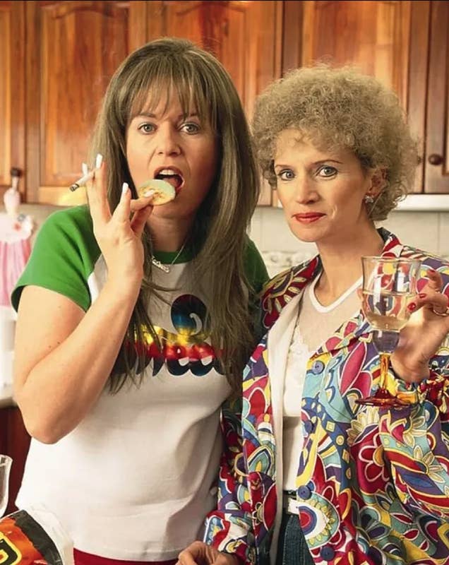 Kath and Kim; Kim is smoking a cigarette and holding a cracker to her mouth while Kath is holding up a glass of white wine