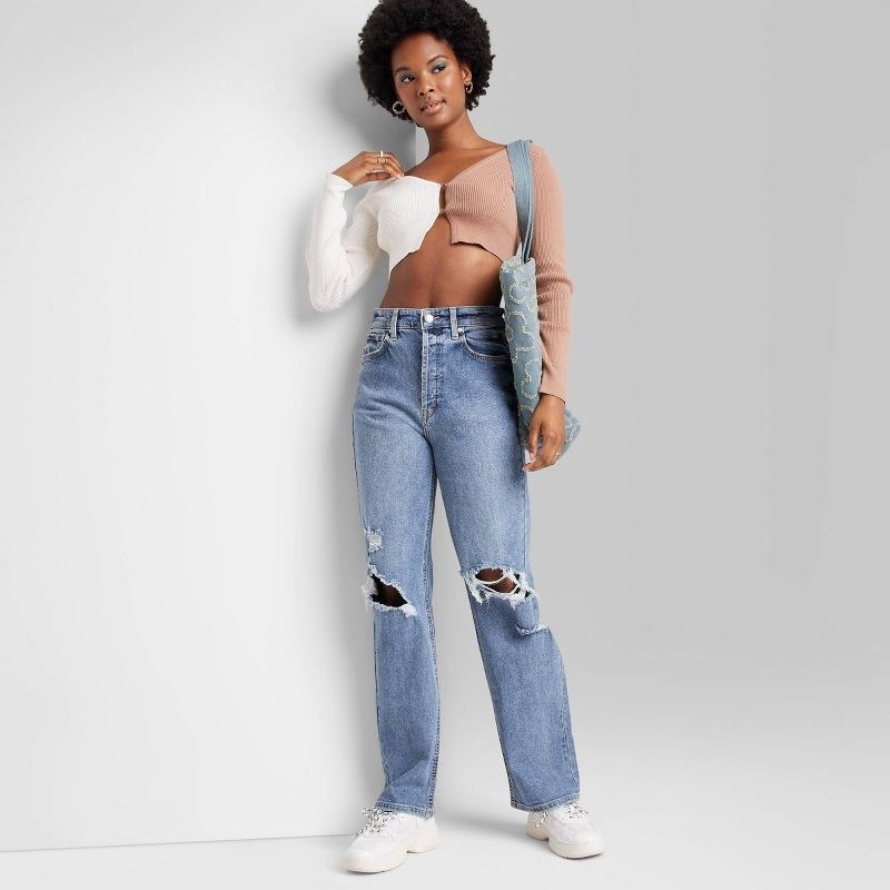 model wearing high-rise distressed straight jeans with a pink and white crop top