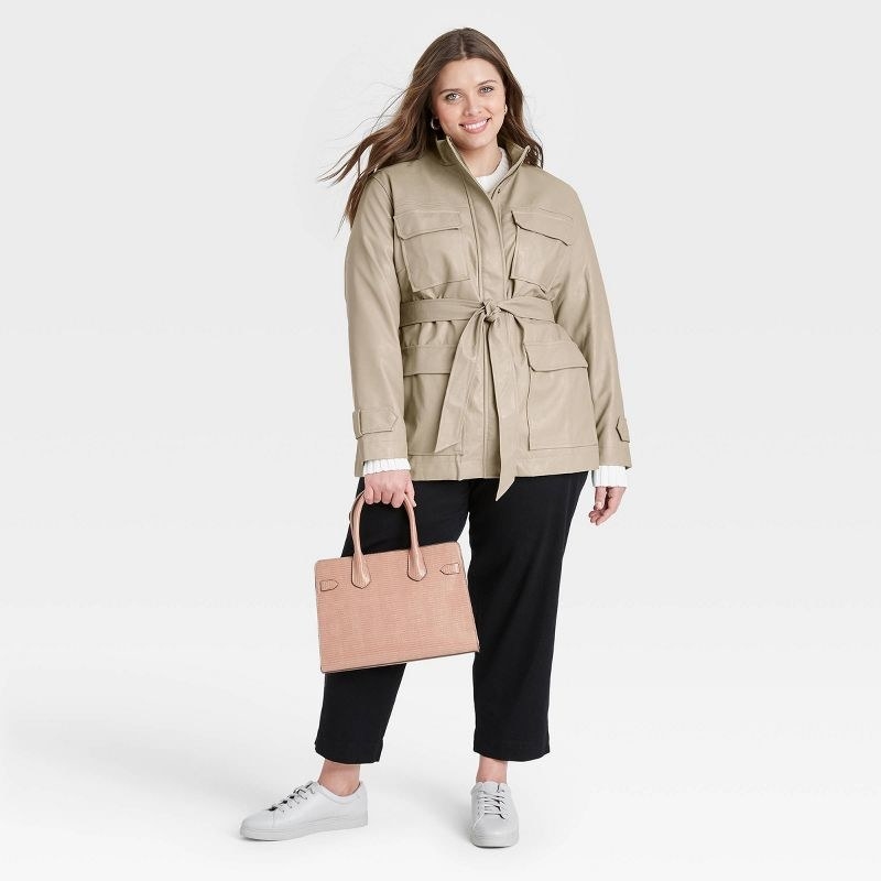 model wearing tan anorak jacket tied carrying a pink purse