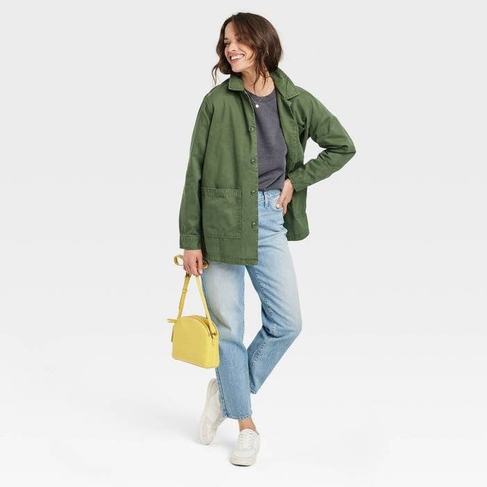 model wearing green utility chore jacket carrying a yellow purse
