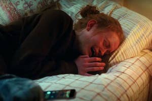 A close up of Sadie Sink crying in bed