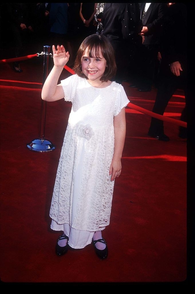 Mara Wilson as a child waving on the red carpet