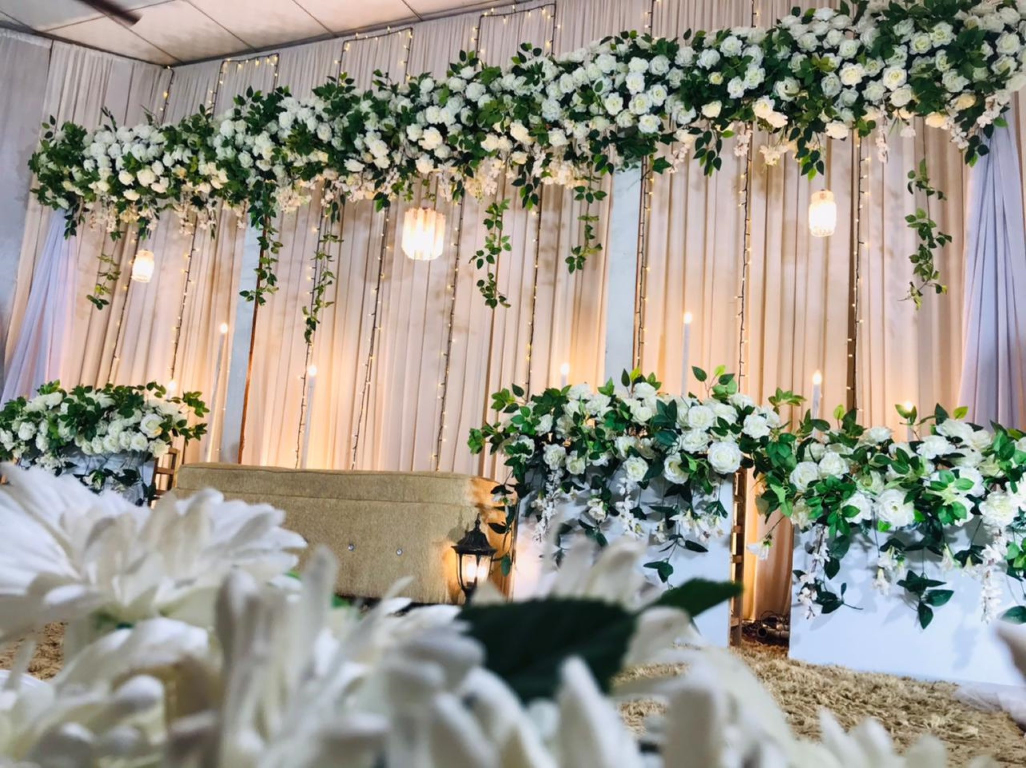several white flowers are decorated in a hall for a wedding