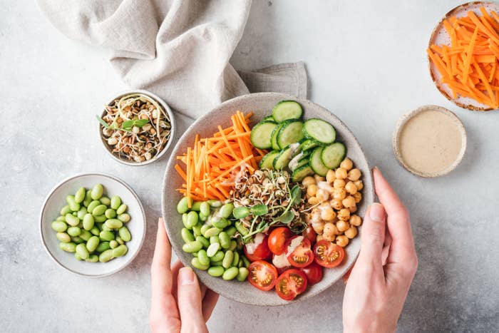 Prepping a cucumber salad with tomatoes, chickpeas, and carrots