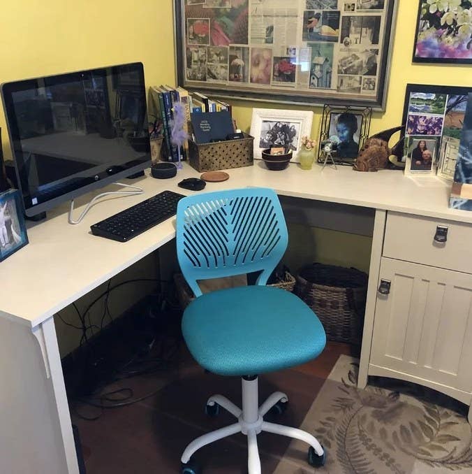 A reviewer&#x27;s image of a turquoise mesh task chair