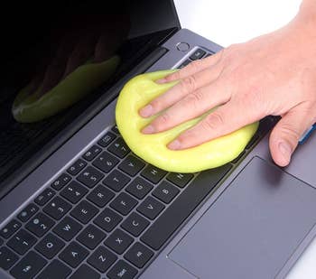 person using the cleaning gel on a laptop keyboard