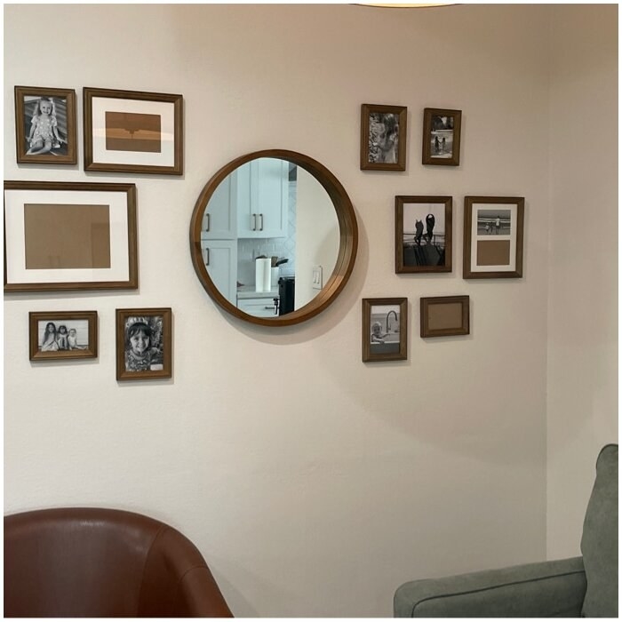 Brown frames on wall surrounding round mirror