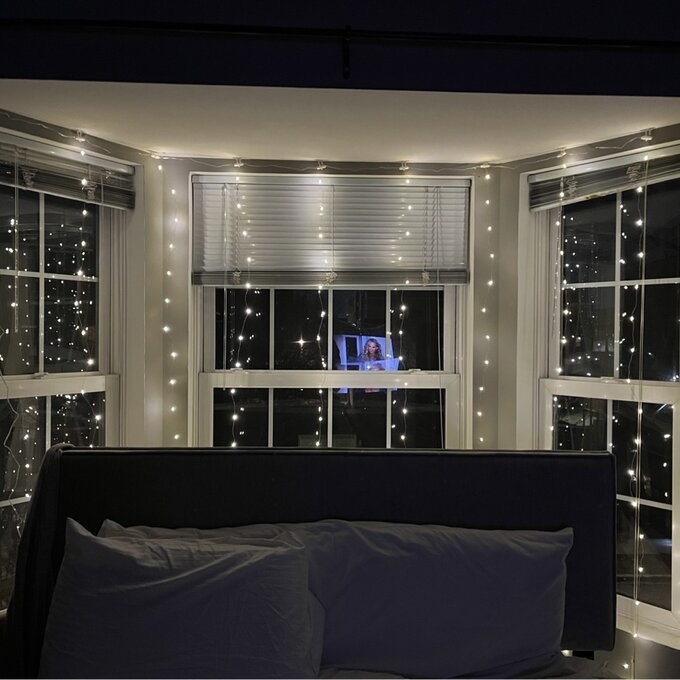 Fairy lights hanging over window behind bed