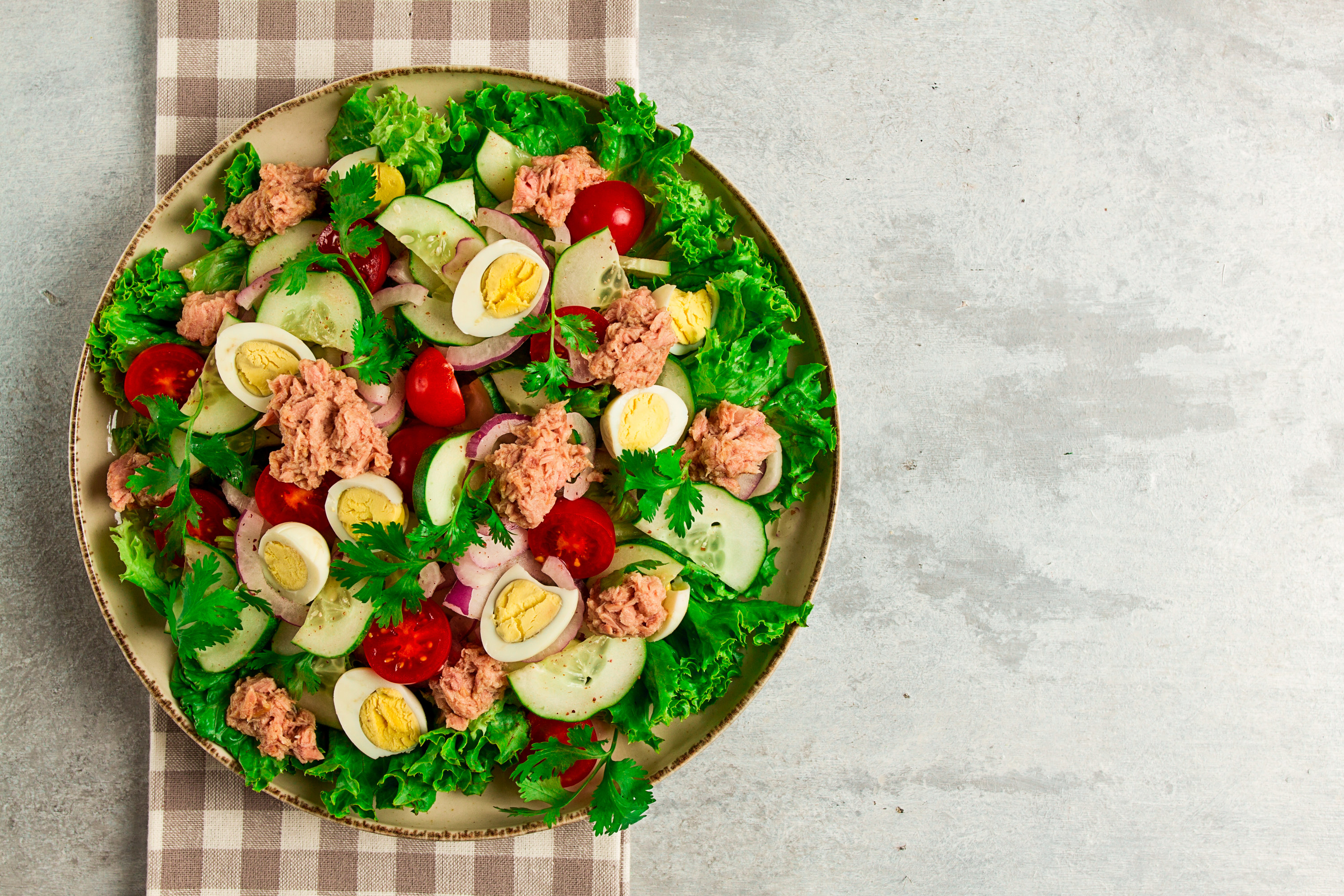 Tuna salad on a bed of lettuce with hard boiled eggs, tomatoes, and cucumbers on top