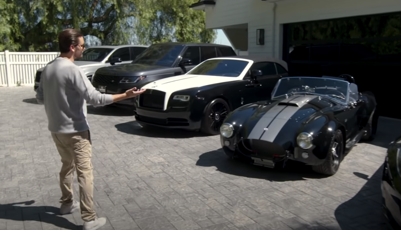 Scott standing in front of four luxury cars