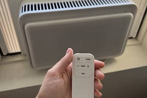 the window unit and a hand holding the remote