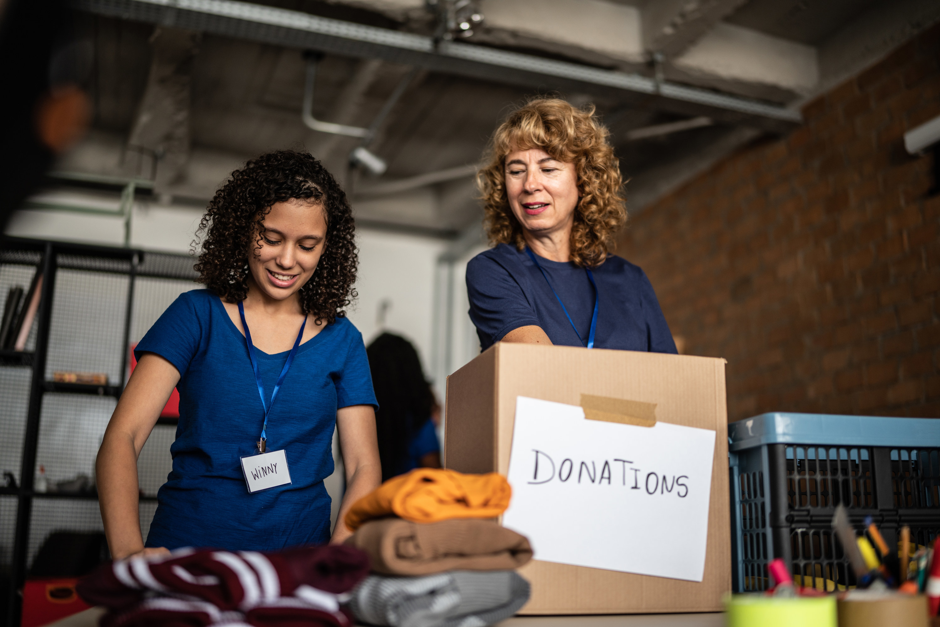 women putting clothes into a donation box