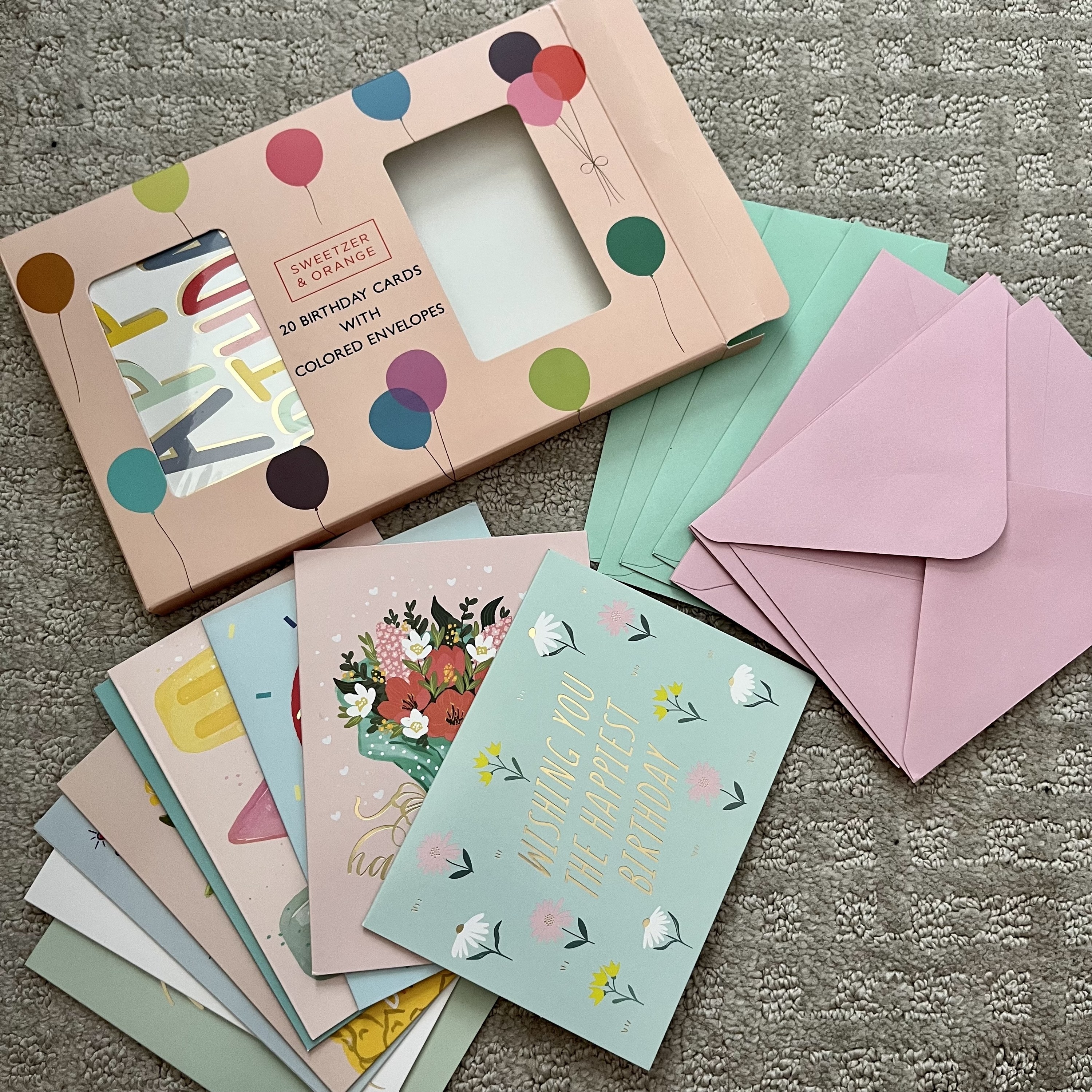 The birthday cards and envelopes spread out on a carpet