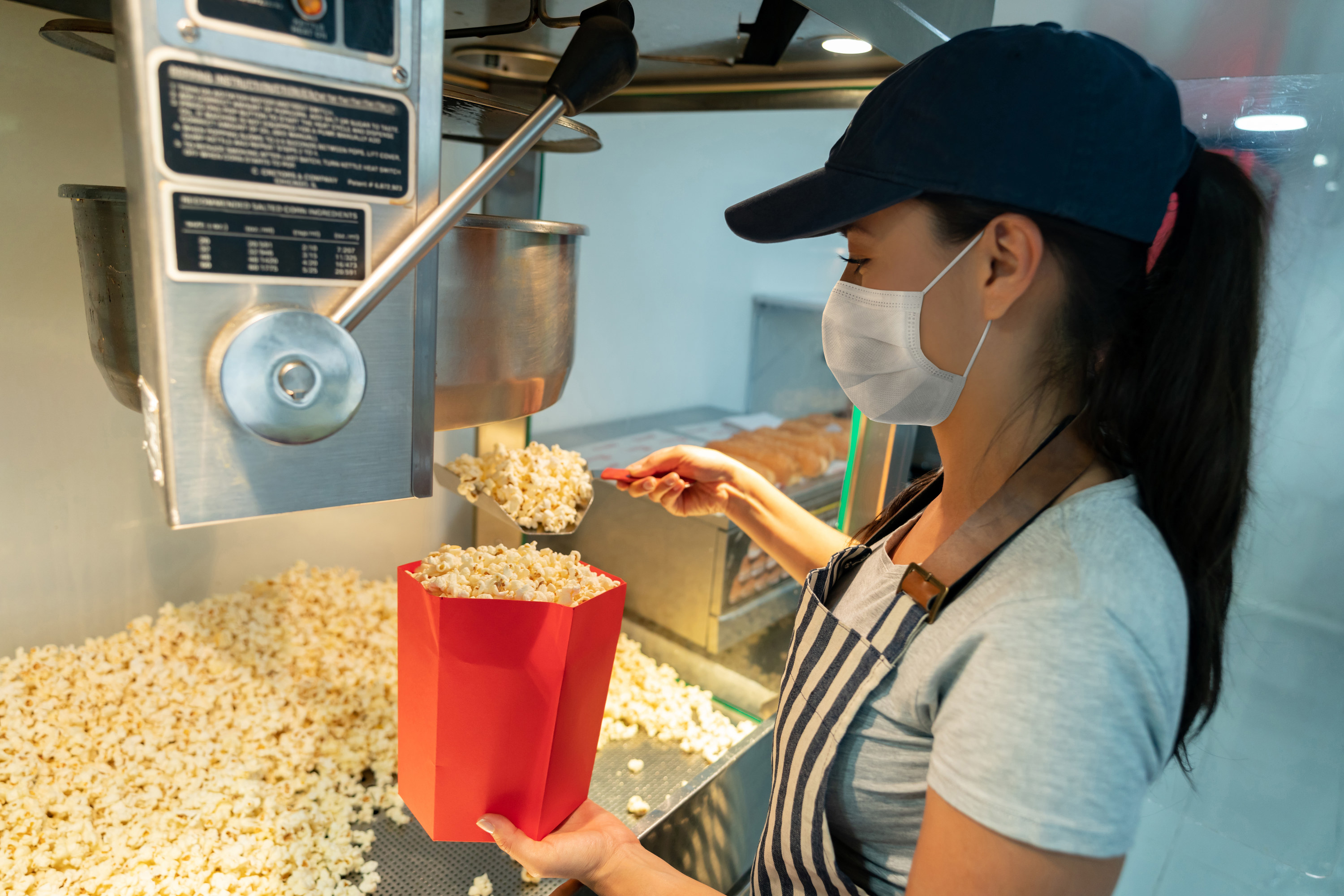 Movie theater employee scooping popcorn