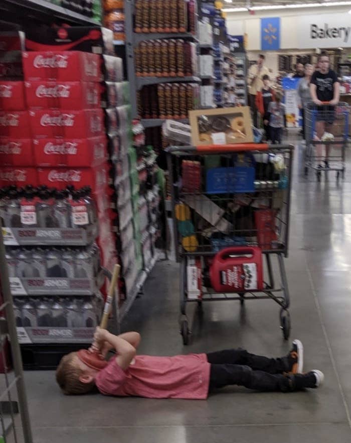 a kid lying on the floor and plunging his face with a toilet plunger