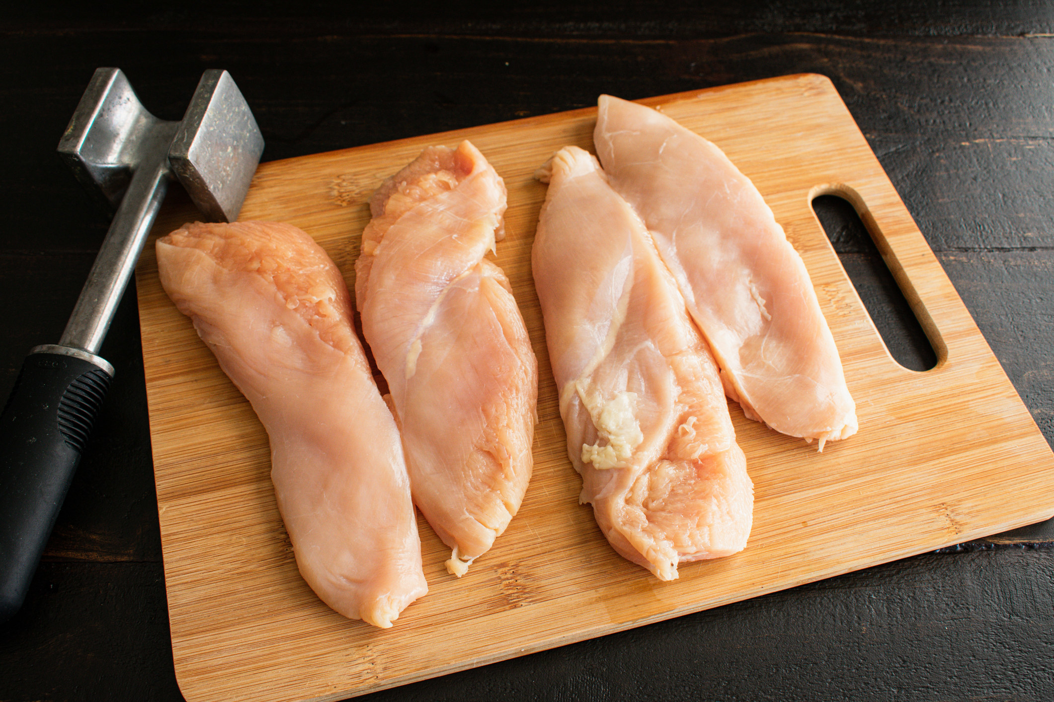 Pounded chicken breasts on a cutting board.