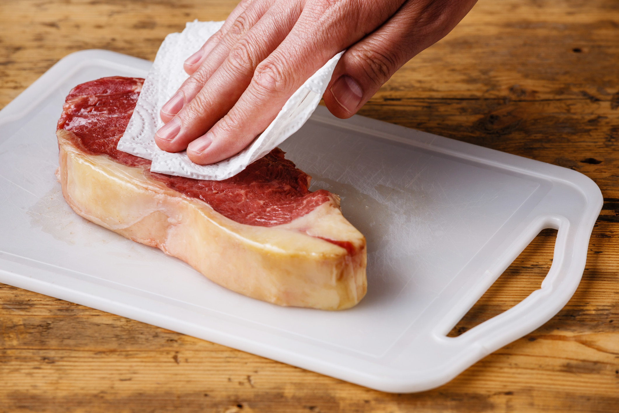 Patting a steak dry with paper towel.