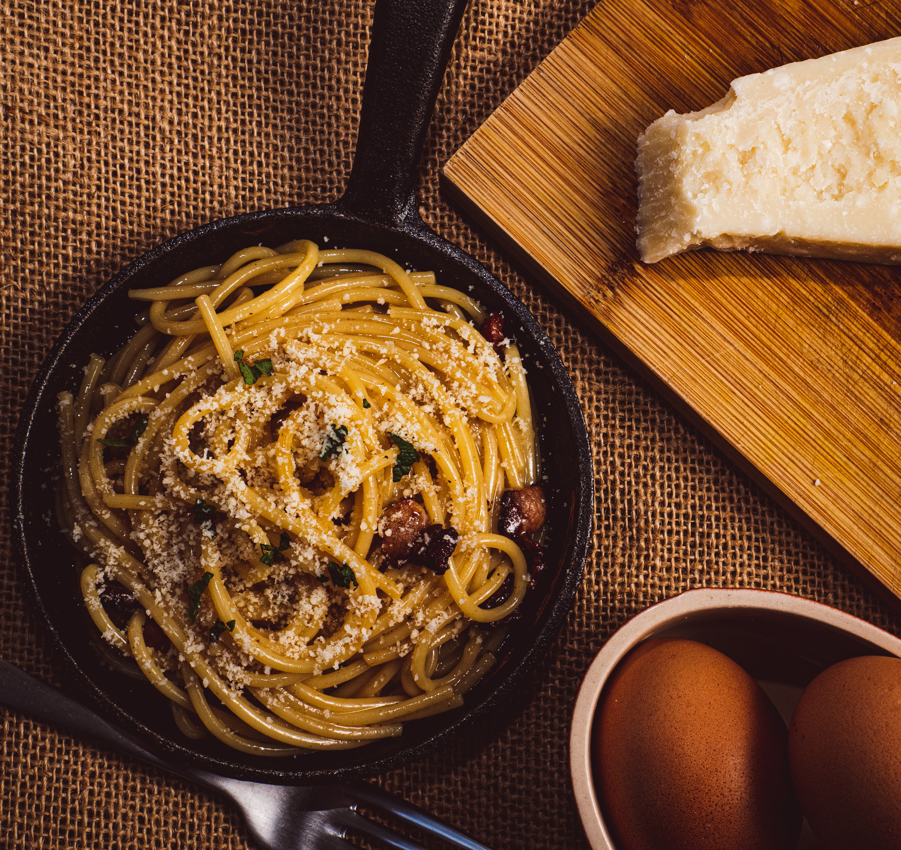 An above-shot of pasta next to eggs and Parmesan.