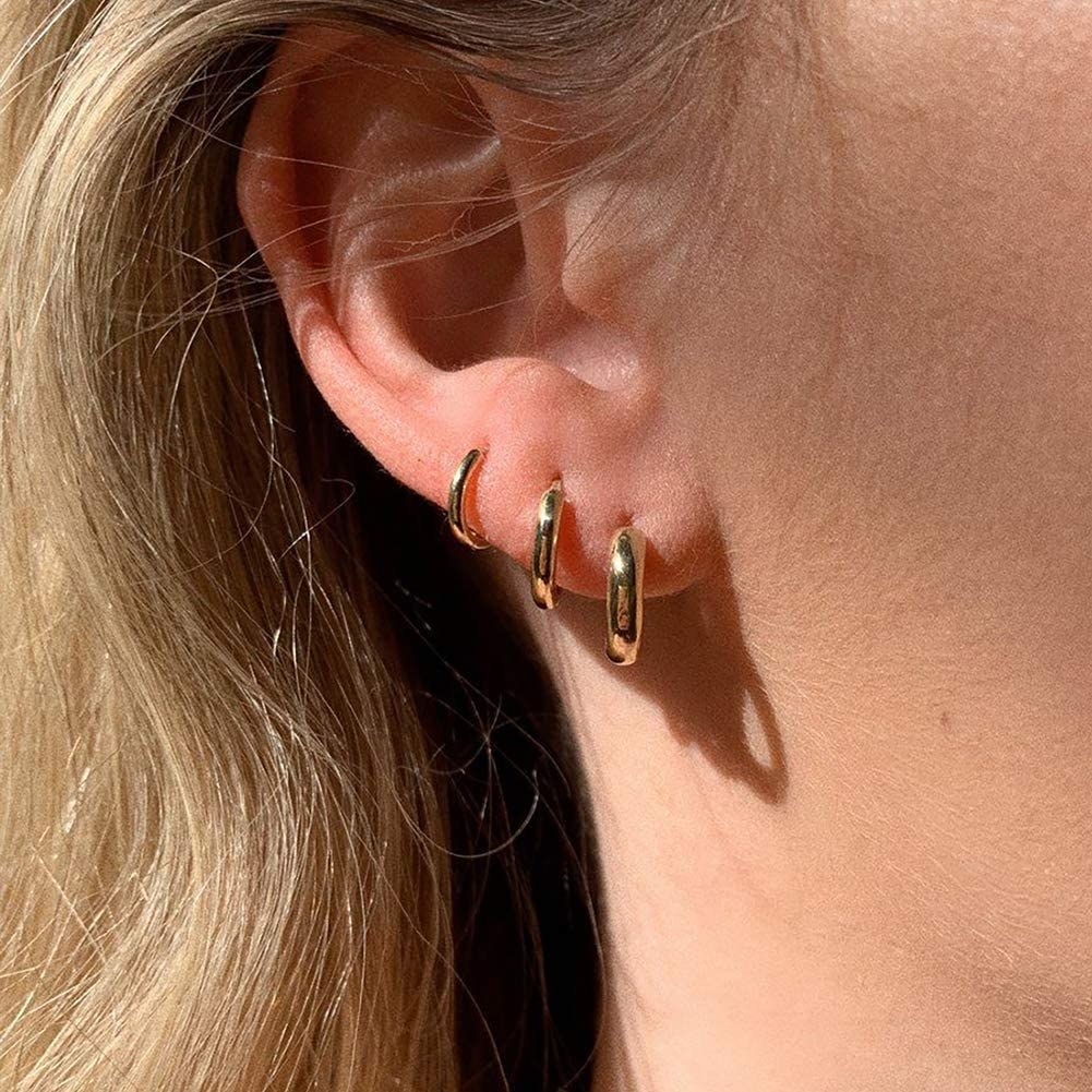 three small hoop earrings on an ear
