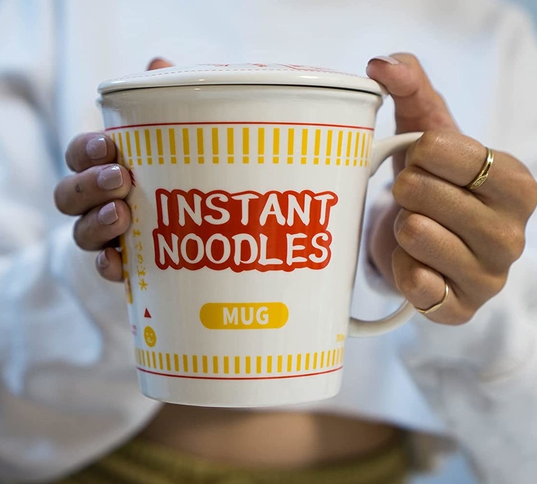 a person holding the instant noodle mug