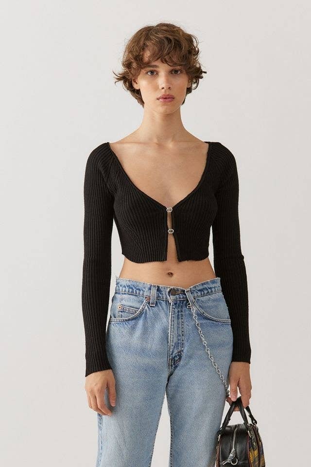 model in black scoop neck cropped ribbed cardigan with two silver clasps