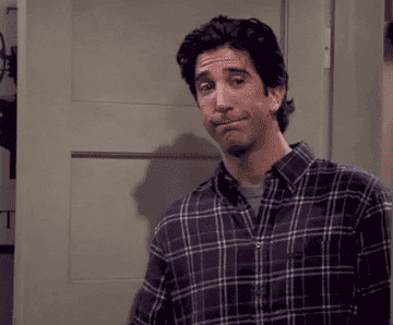 Ross from Friends make a gesture to show he wants the others to keep the noise down while pulling an obnoxious facial expression