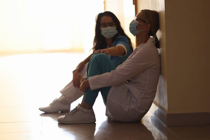 two nurses sitting on the hallway floor