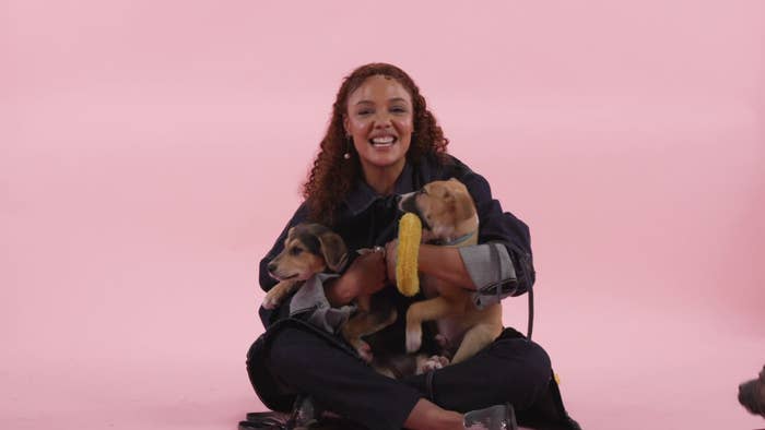 Tessa smiling widely as she hugs two puppies