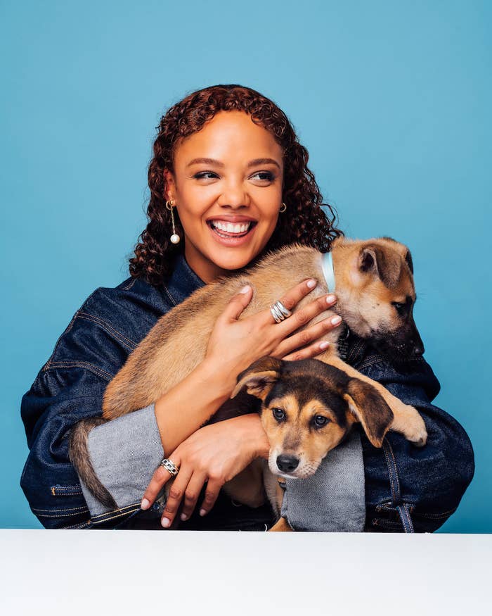 A closeup of Tessa as she smiles widely as she holds two puppies in her arms