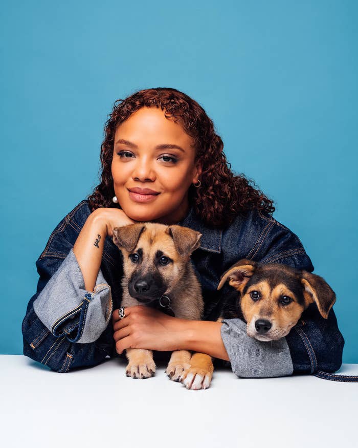 Tessa leans on a table as she holds two puppies