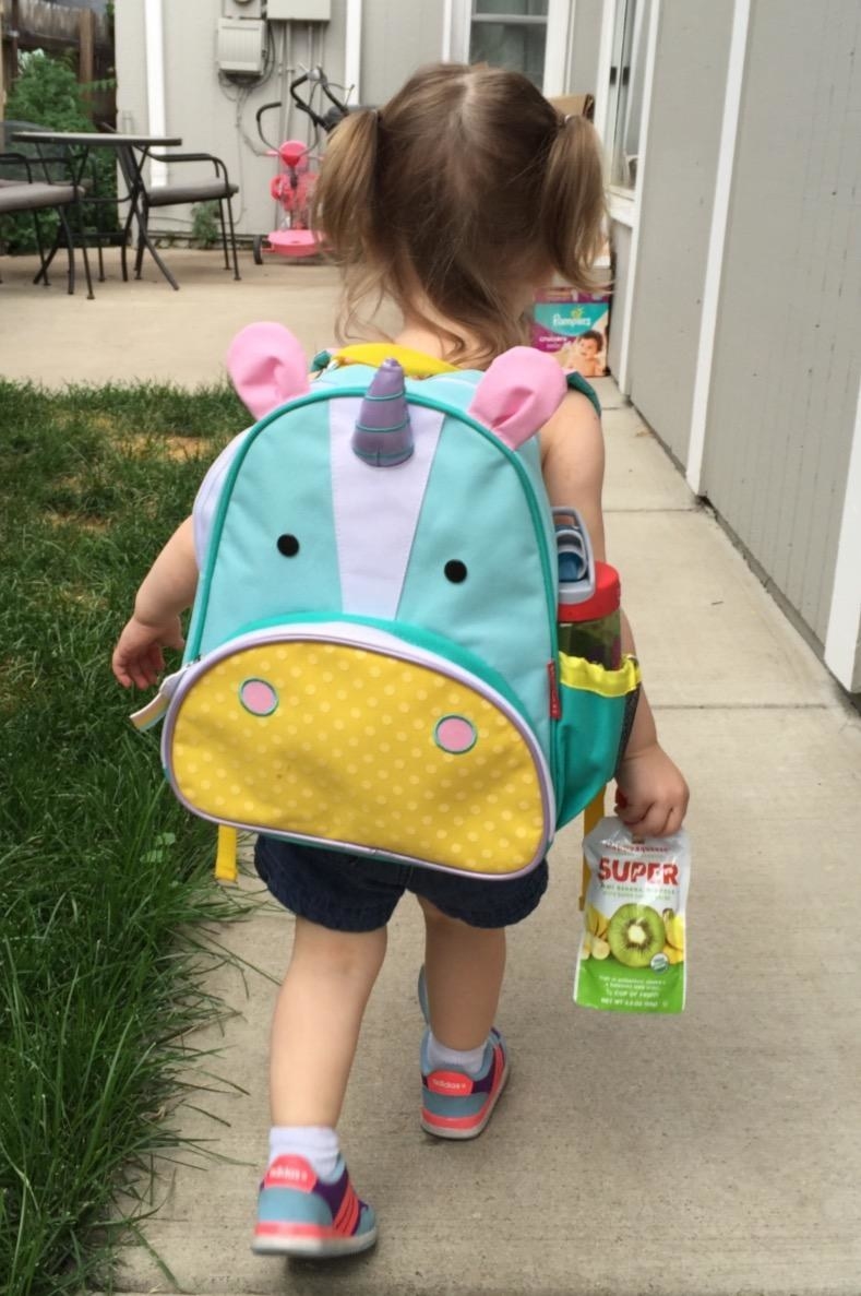 reviewer's photo of their child wearing the unicorn backpack