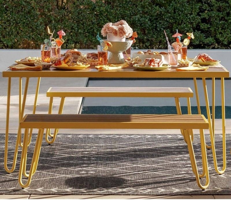Two benches and a table with wood top and yellow metal legs