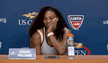 Serena Williams makes a shrugging gesture at a press conference