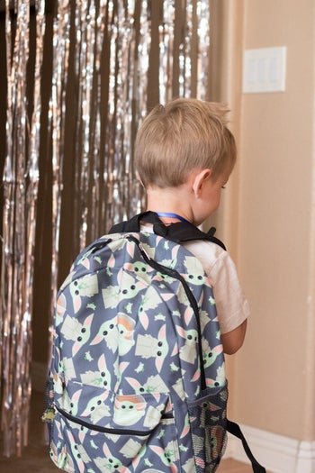 reviewer's photo of their child wearing the Baby Yoda backpack