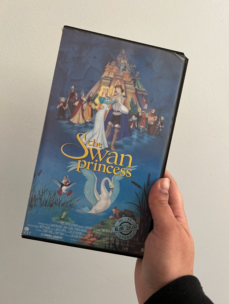 A hand holding a VHS copy of The Swan Princess