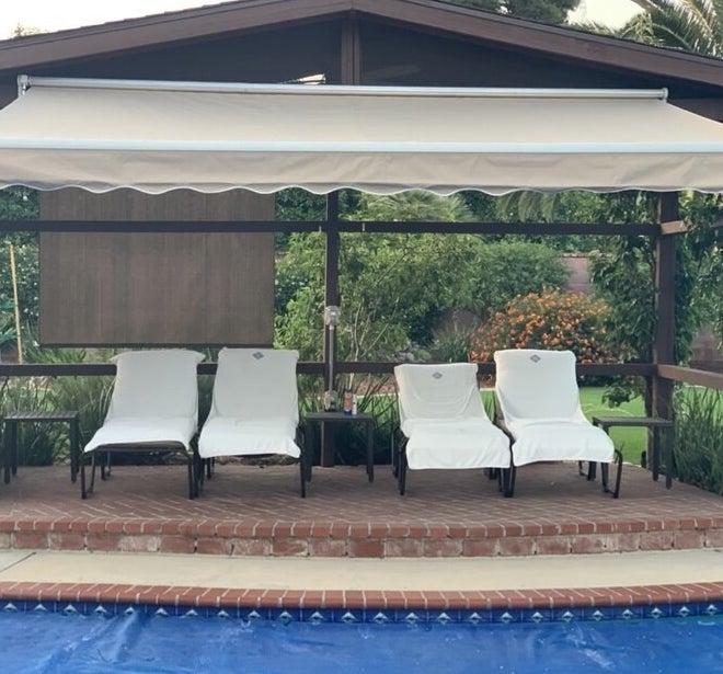 Awning shading four chairs by a pool