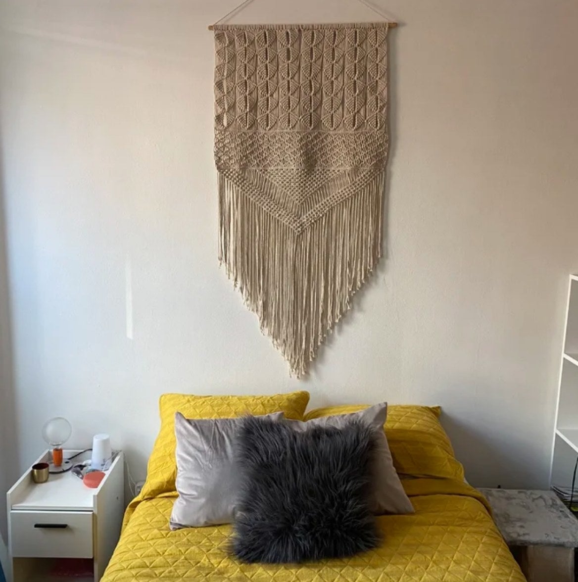 Macrame wall tapestry hanging over yellow bed