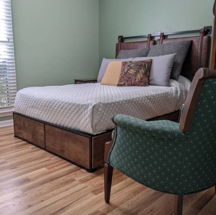 Wooden platform bed with gray guilt on it