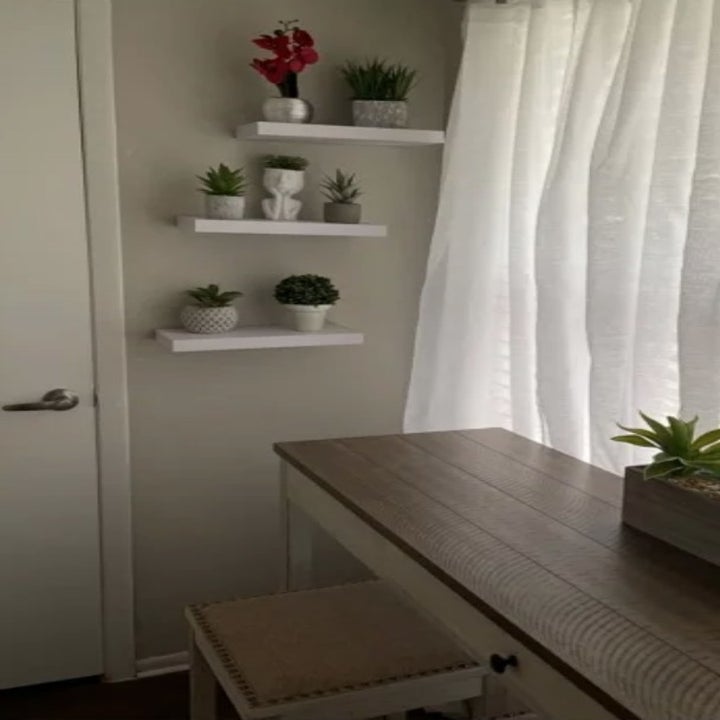 White floating shelves on wall in front of console table