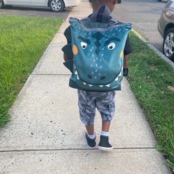 reviewer's child wearing the dino backpack