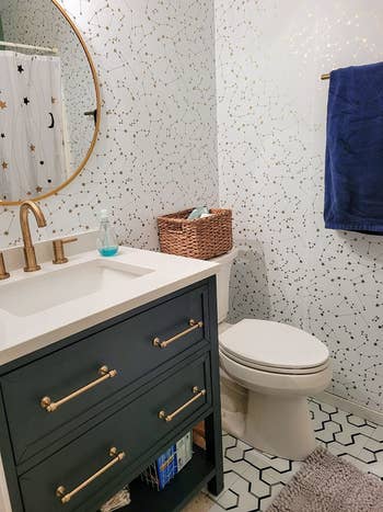 A bathroom's walls are covered in the frost colored Novogratz Constellations Removable Peel and Stick Wallpaper in Frost