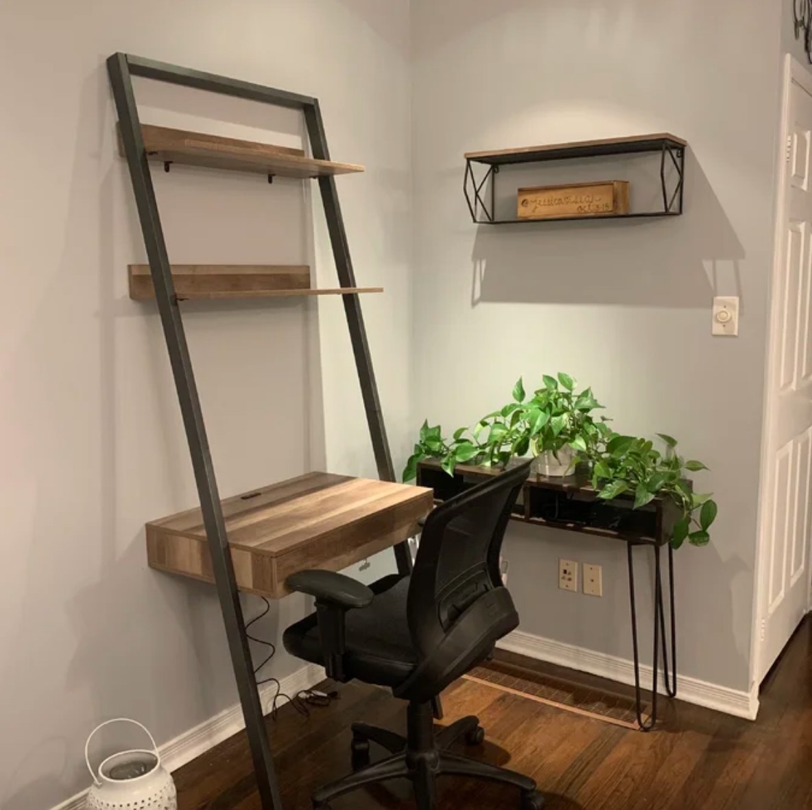 Wooden leaning ladder desk with black desk chair in front of it