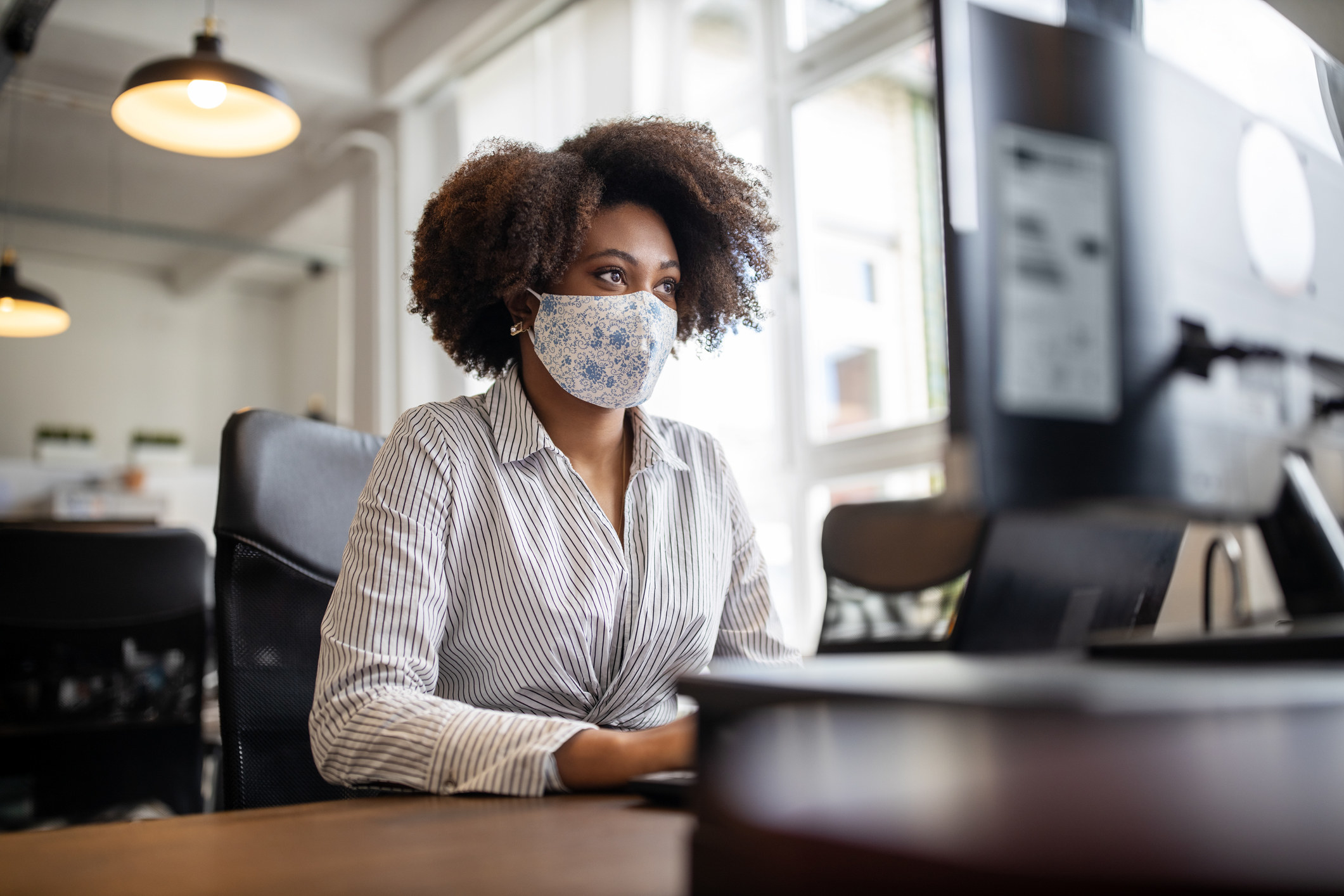 A woman wearing a face mask and working at her computer