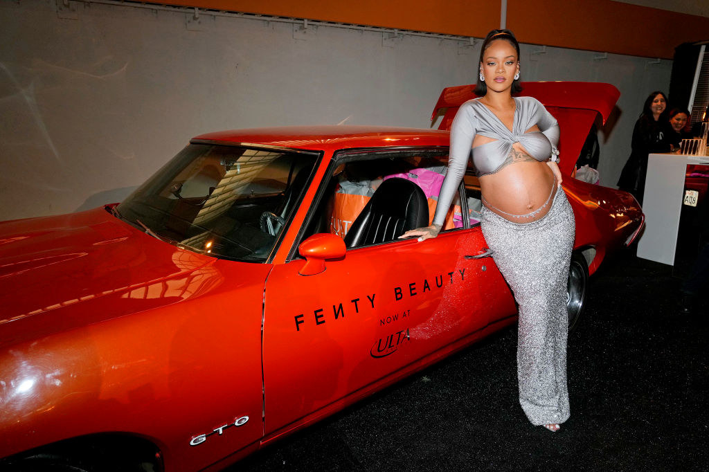 Rihanna leaning on a Fenty Beauty car
