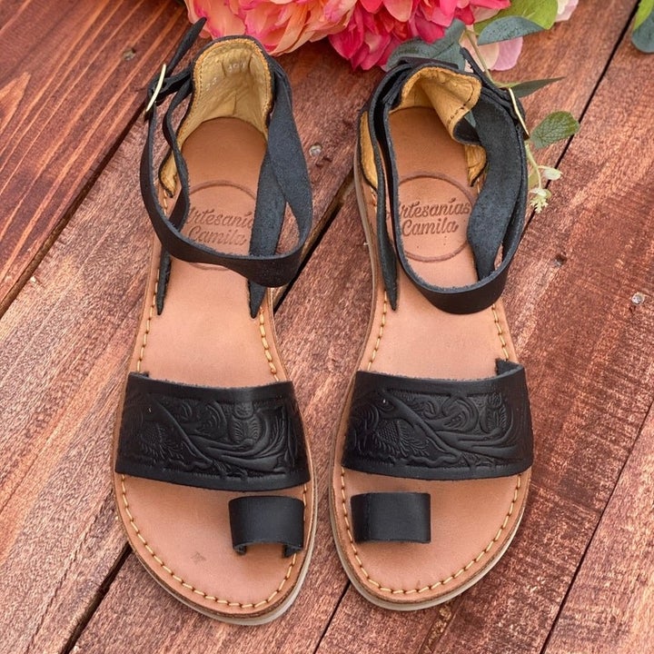 a pair of hand-tooled black leather sandals