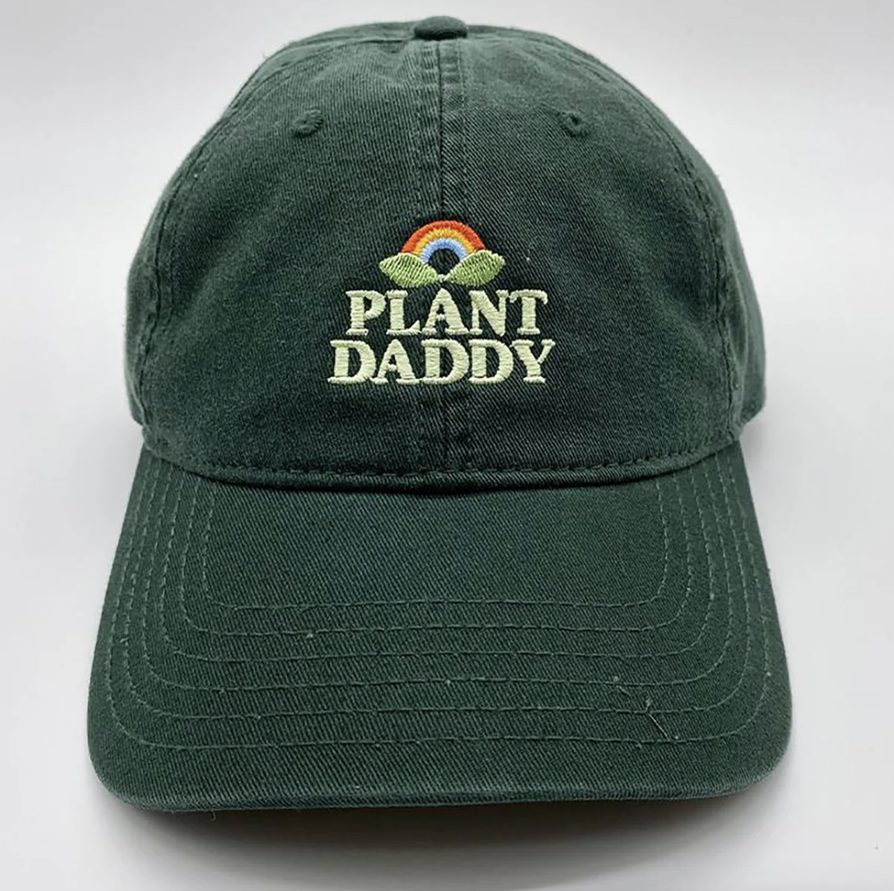 A dark green baseball hat with the words Plant Daddy are sewn into it
