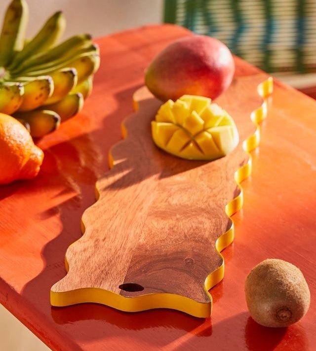 a wave-edged wooden board with mangos on it