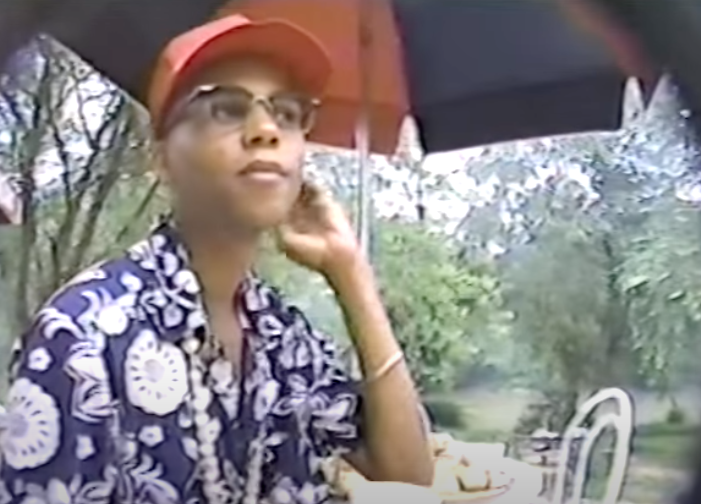 RuPaul in a floral print button down and baseball cap